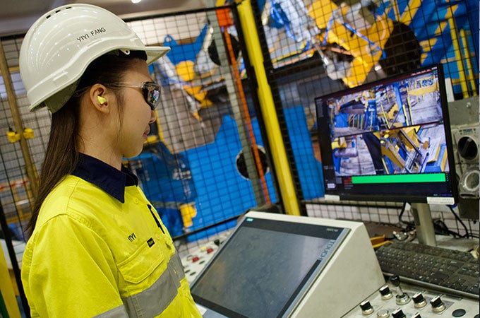 Female worker in protective gear looking at a computer screen